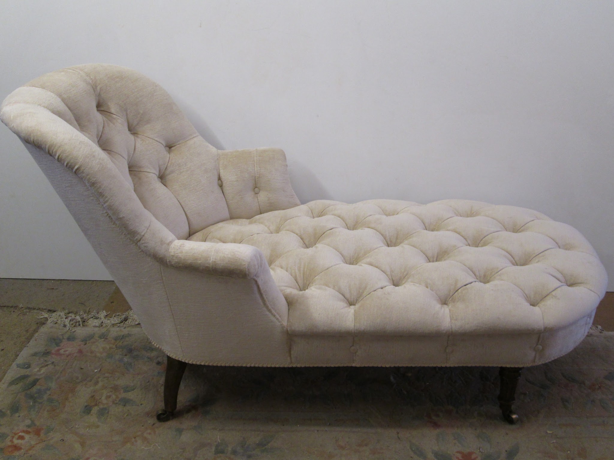 A buttoned chaise longue finished in ivory fabric