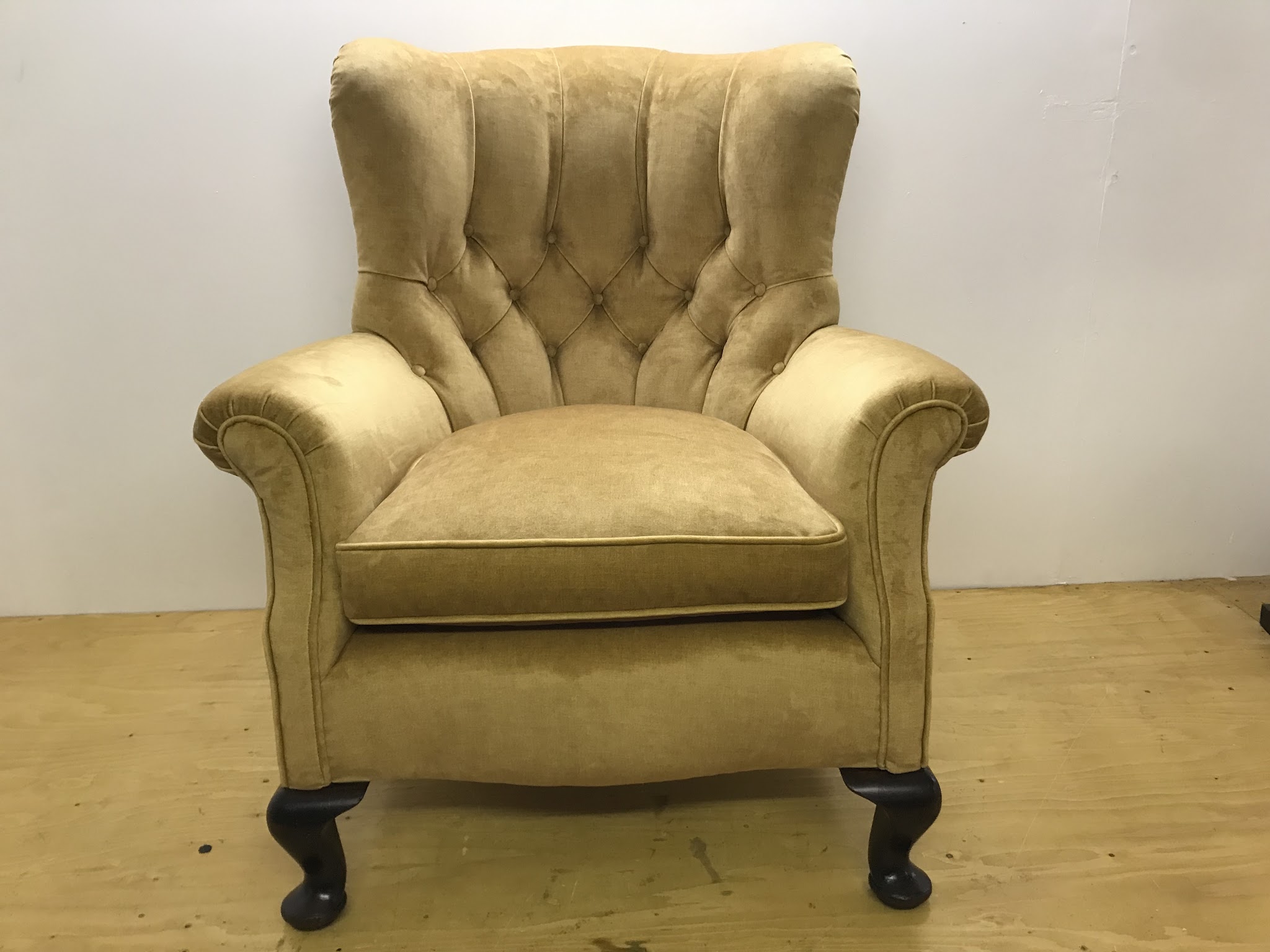 A buttoned-back armchair in gold velvet on cabriole legs