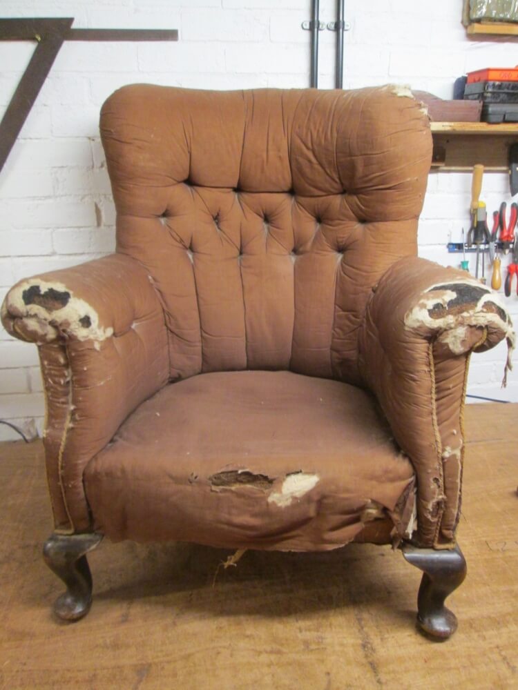 A worn buttoned armchair before restoration