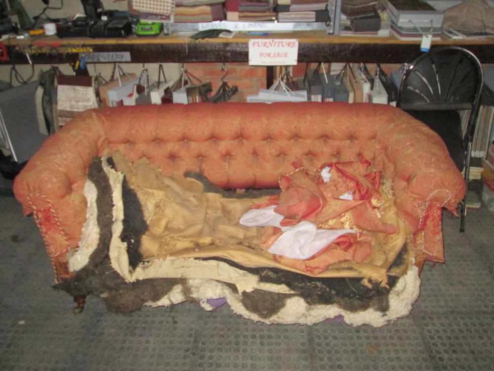 A buttoned sofa with its old covers coming off